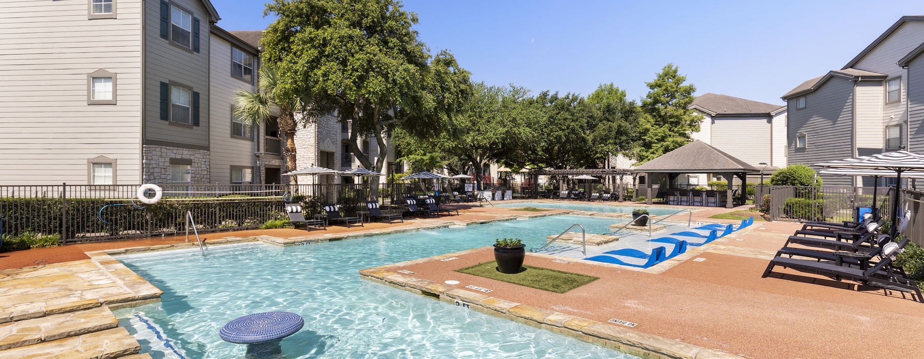 Large sparkling blue pool with a large pool deck and lounge chairs